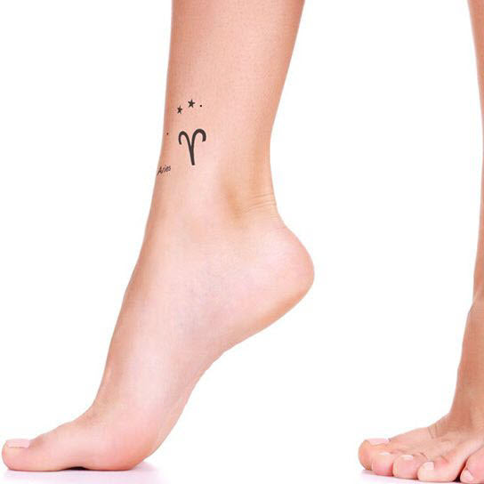 Minimalist Aries zodiac symbol tattoo on the upper arm.